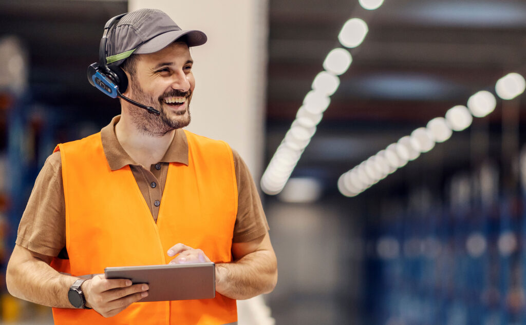 Ein Logistik-Mitarbeiter schaut auf eine Checkliste in seinen Händen und lächelt.