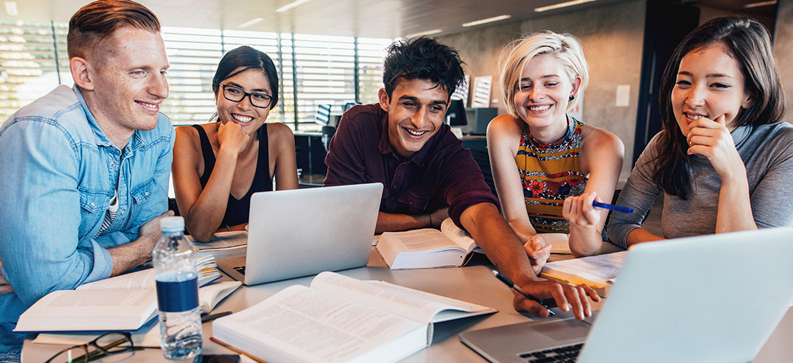 s-Business-Meeting Studenten sitzen an einem Tisch voller Laptops zusammen und lernen zusammen.