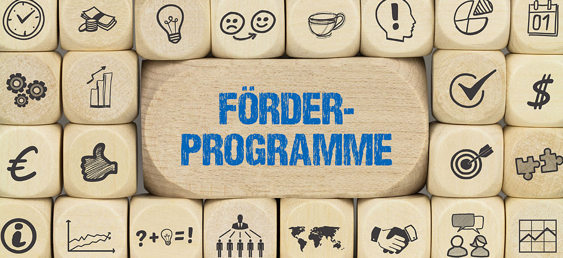 Lauter Holzwürfel mit verschiedenen Symbolen. Auf einem großen Würfel steht: Förderprogramme