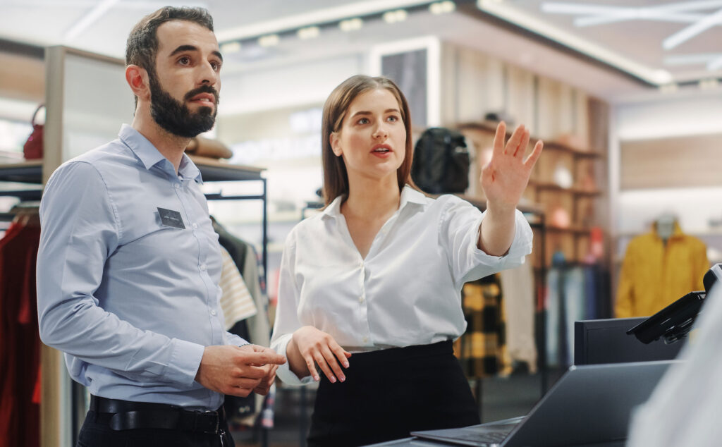 Eine Verkäuferin erklärt ihrem Kollegen etwas im Geschäft.