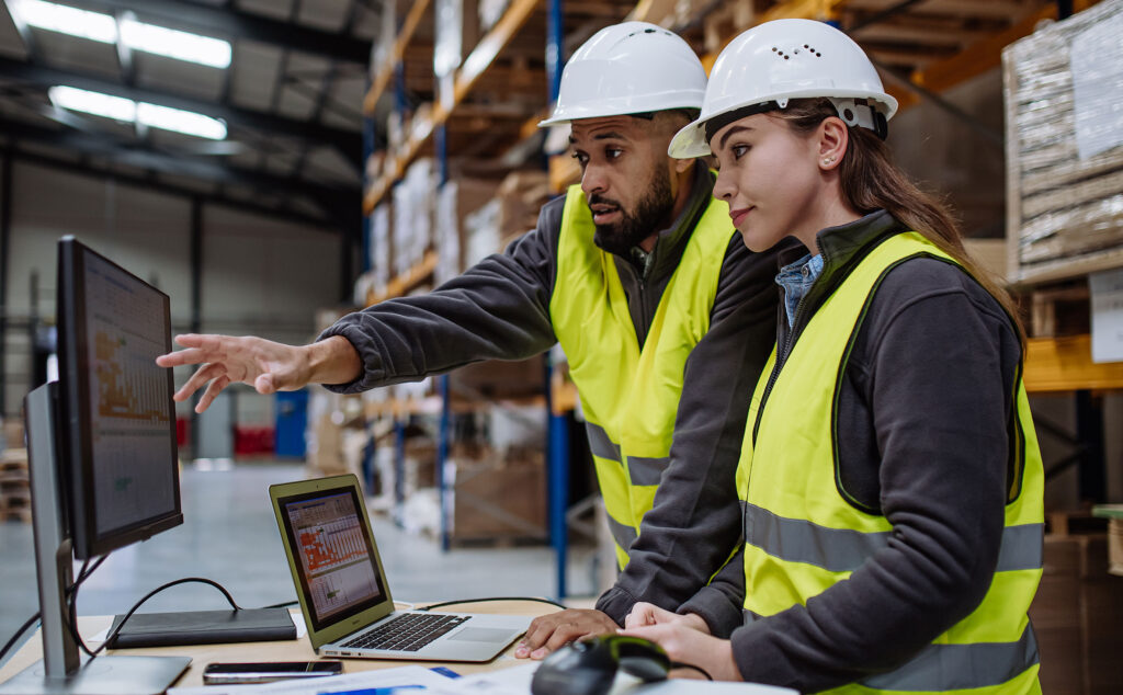 Ein Mann erklärt einer Frau am Laptop etwas und zeigt auf den Bildschirm.