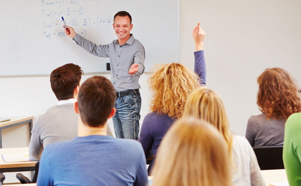 Header-Unterricht-Studium-07 Ein Dozent erklärt seinen Schülern etwas am Whiteboard.
