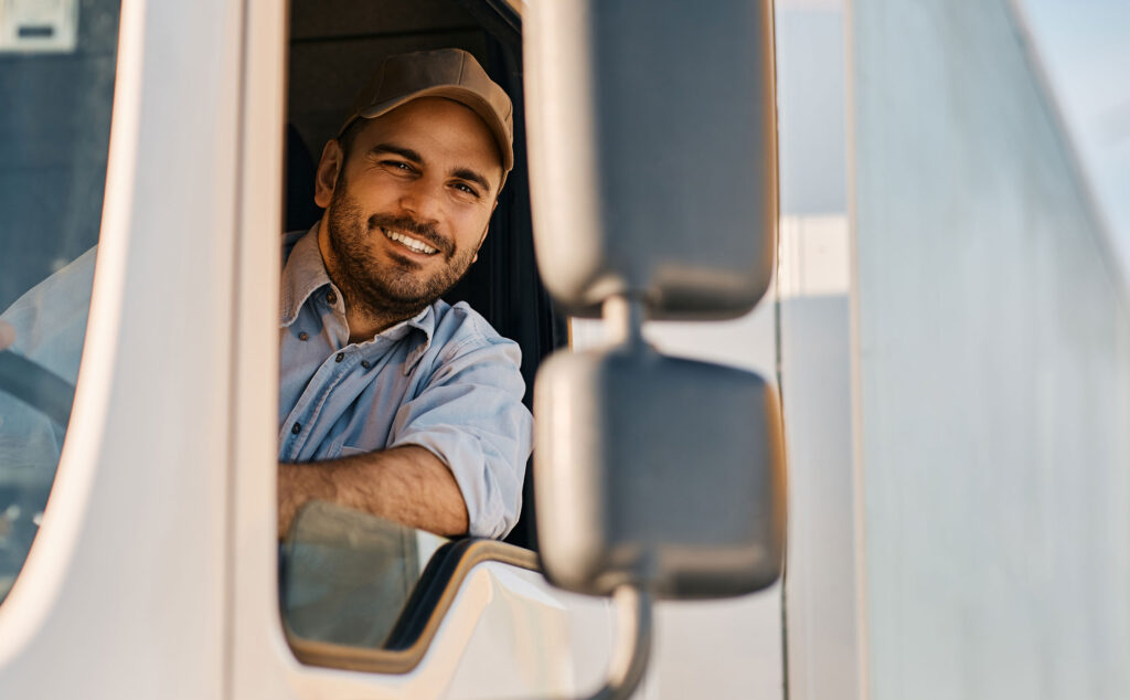 Mann sitzt im Führerhaus eines LKW´s und schaut aus dem Fenster.