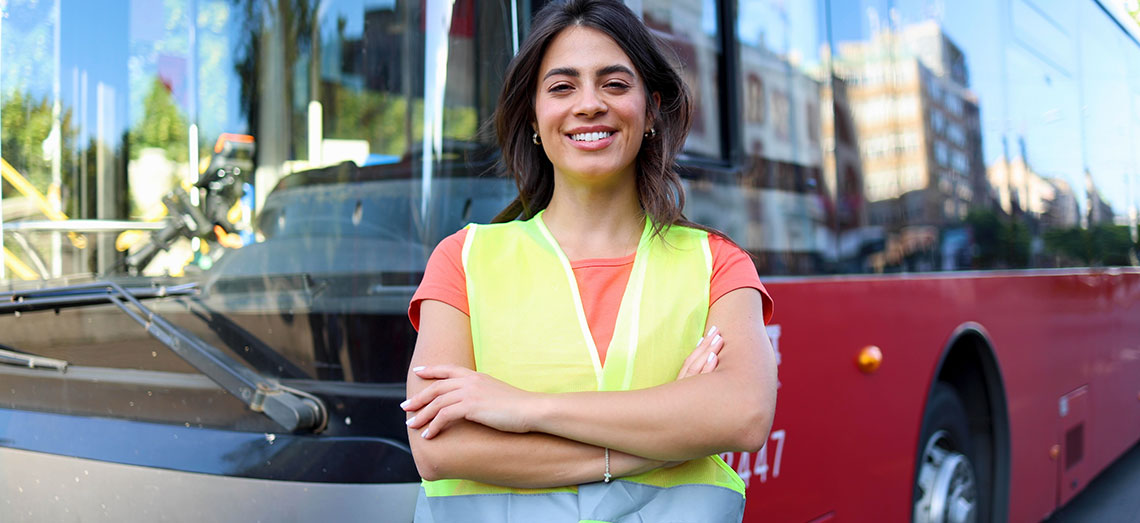 ZB-Meister-Kraftverkehr-03 Frau steht vor einem Bus und lächelt in die Kamera.