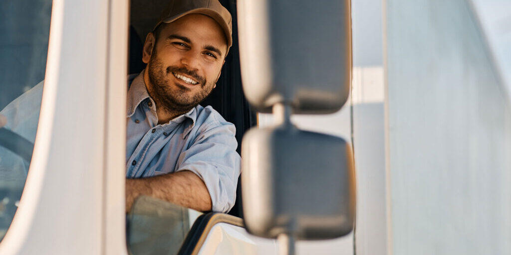 Mann sitzt im Führerhaus eines LKW´s und schaut aus dem Fenster.