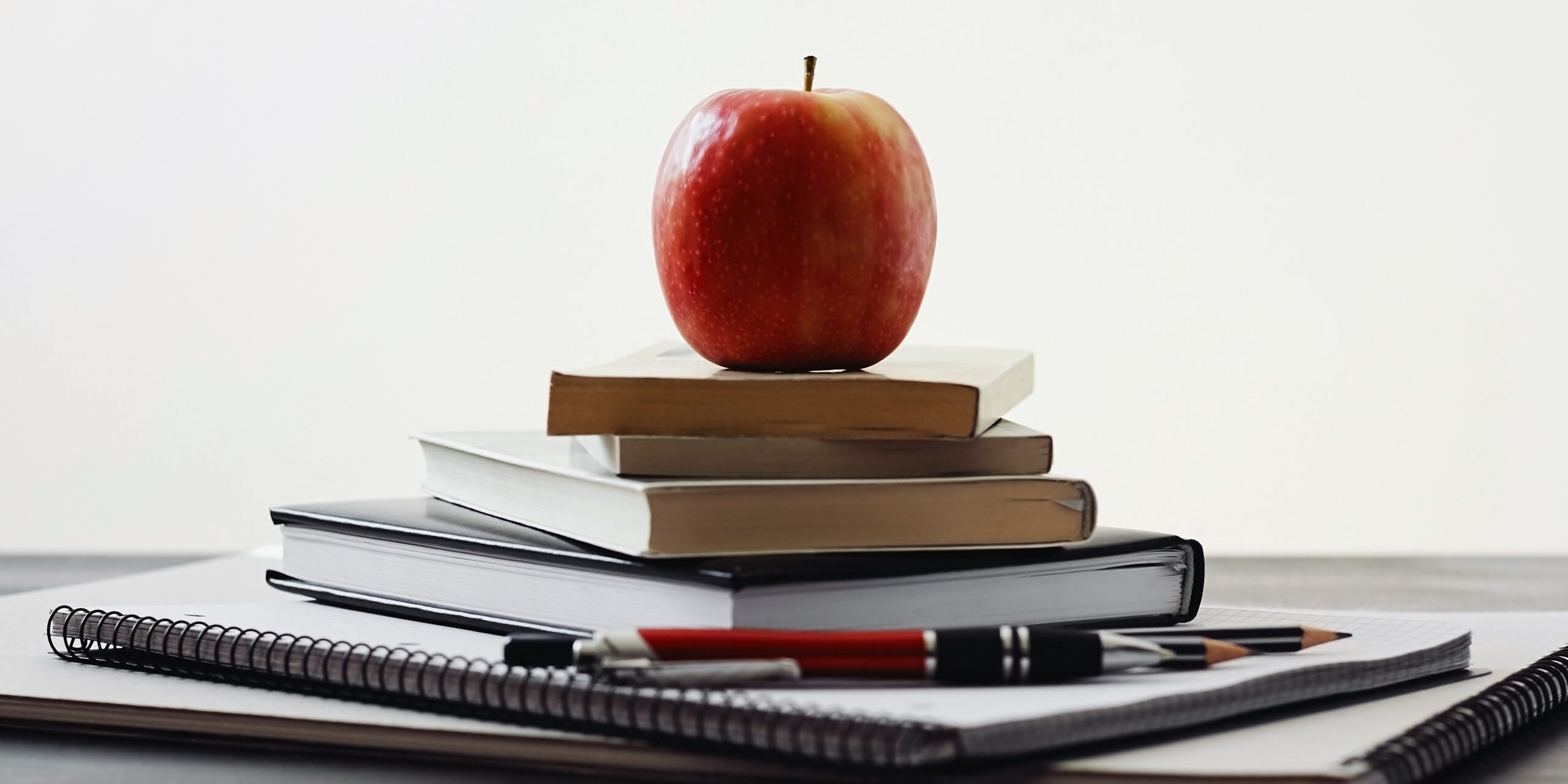 Auf einem Stapel Notizbücher liegt ein Apfel.